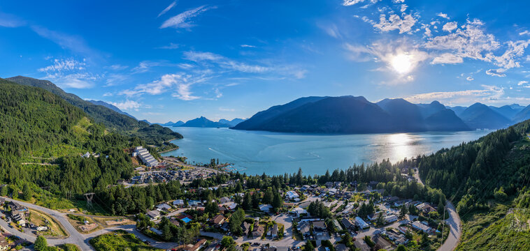 Panoramic Aerial View of Britannia Beach Village Overlooking Mountains, Water and Sunlit Coastline in British Columbia
