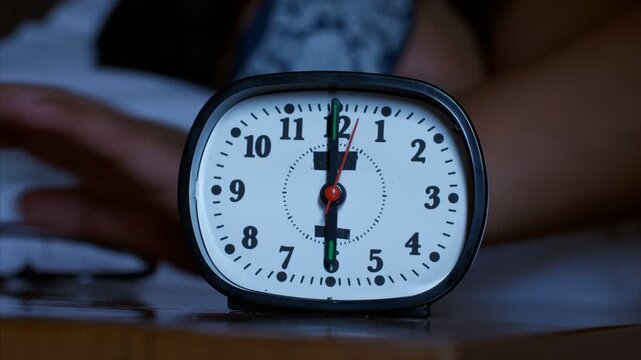 Close-up shot of a sleepy man finding snoozing alarm clock to turn off. Indian image of a man laying on the bed and sleeping wearing night mask searching alarm clock