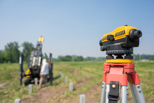 Diesel hammer drives concrete piles for a country house. Surveying equipment on a tripod set up. 