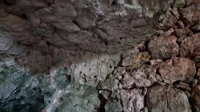Xemxija, Malta 29.07.2026 - Heritage trail, Roman Baths, shelf like cut in the stone Dark cave walls show rough, textured surfaces. Greenish moss grows on damp, uneven stone. Light filters through nar