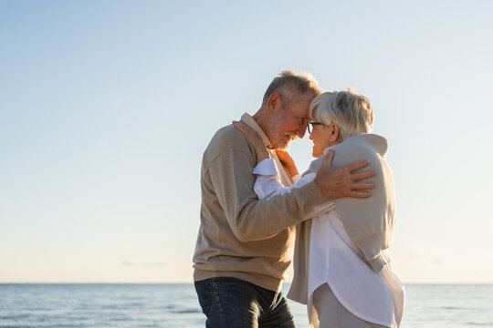 Senior mature couple hugging enjoying outdoor recreation walking on beach. Old husband wife embracing with tenderness love enjoying sweet bonding. Grandmother grandfather together. Family moment love