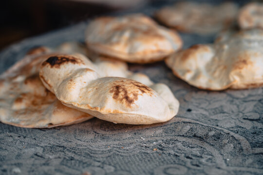 View of freshly baked local Siwa bread with charred spots resting on a patterned fabric surface in Siwa, Marsa Matrouh Governo, Egypt.