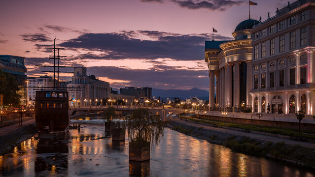 Sunset view of a river and buildings in a city of Skopje at dusk