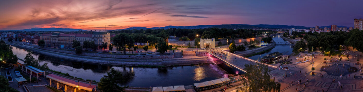 Sunset view of the city  of Nis along a river with buildings and a bridge