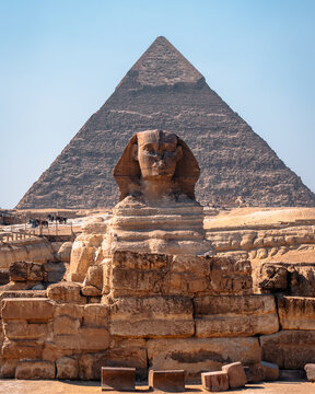View of the Great Sphinx of Giza with the Great Pyramid of Giza in the background under a clear blue sky in Al Haram, Giza Governorate, Egypt.