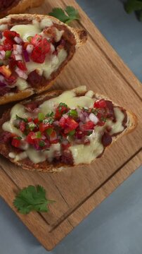 Overhead view of delicious warm molletes with melted cheese, chorizo and pico de gallo salsa, ready to eat