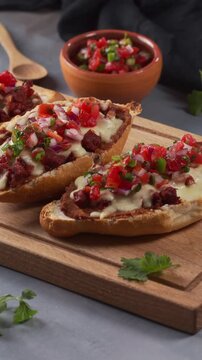 Toasted bolillo bread topped with beans, melted cheese, chorizo and fresh vegetables