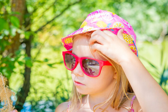 Happy little girl wearing pink fruit print bucket hat and sunglasses, sunny summer day outdoors, Sun protection, safety in hot weather, child fashion and style, children vacation travel lifestyle