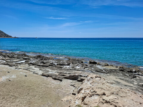 Rocky coastline and sandy shore meet the blue Mediterranean Sea in Calpe, Spain on a clear day