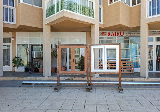 Calpe, Spain - May 27, 2026.Wooden sample window frames on display in front of a window installation shop in Calpe, Spain