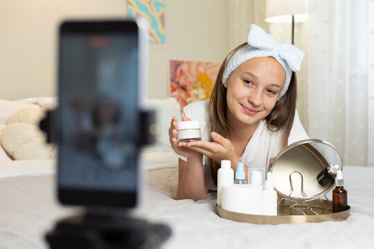 Teenage girl recording skincare beauty vlog with cosmetic product at home