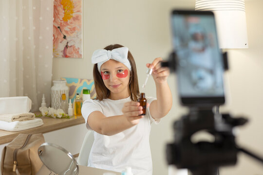 Teenage girl recording skincare beauty vlog with cosmetic product at home