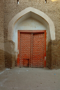 View of the historic red spiked wooden gate at the entrance of Kot Diji Fort, featuring intricate brickwork and an arched doorway in Kot Diji, Sindh, Pakistan.