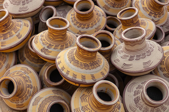 View of traditional handmade earthenware pots with intricate brown and yellow painted patterns stacked together in Thatta, Sindh, Pakistan.