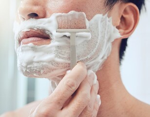 Fototapeta premium Hand shaving foam off the lower face and jaw of a man with a plain razor