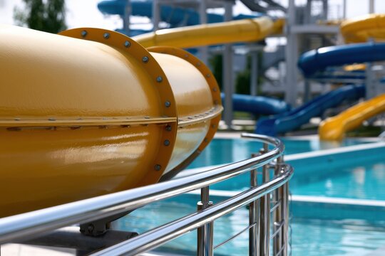 Vibrant outdoor water park with brightly colored twisting slides and clear pool water on a sunny day for family fun and summer recreation