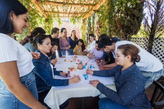 large group of latin people in painting classes in a terrace outdoors in Mexico Latin America, multi generational Hispanic and diverse team meeting in art classes 