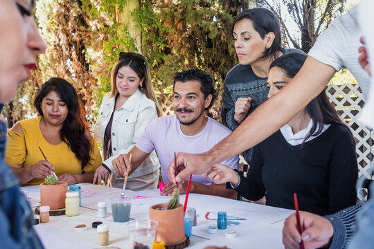 large group of latin people in painting classes in a terrace outdoors in Mexico Latin America, multi generational Hispanic and diverse team meeting in art classes 