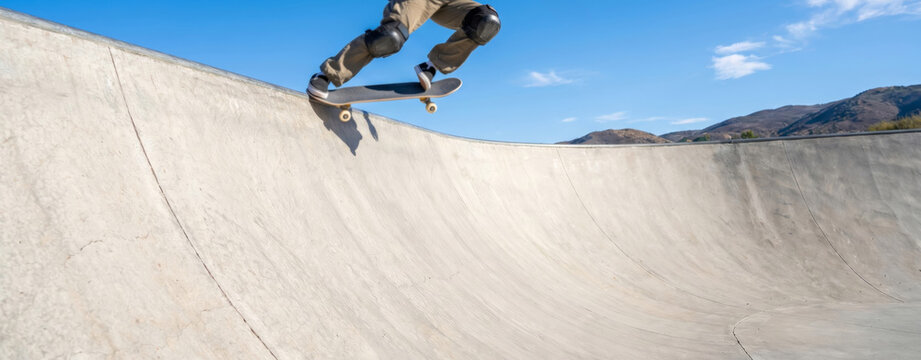 Skateboarder performing trick in concrete skate bowl. Young man practicing extreme sport during Go Skateboarding Day. Athletic hobby and lifestyle in outdoor urban park facility.