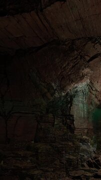 Inside a cave, light filters through a narrow opening. The rocky walls display various textures and shades. The scene captures the natural beauty of the cave environment.