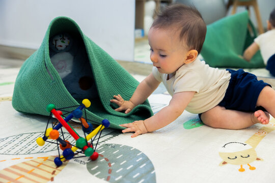 Happy baby crawling on playmat exploring colorful toy