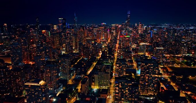Bright lights of vibrant Chicago, Illinois, USA at night. Drone flight over the luminous streets crossing the cityscape.