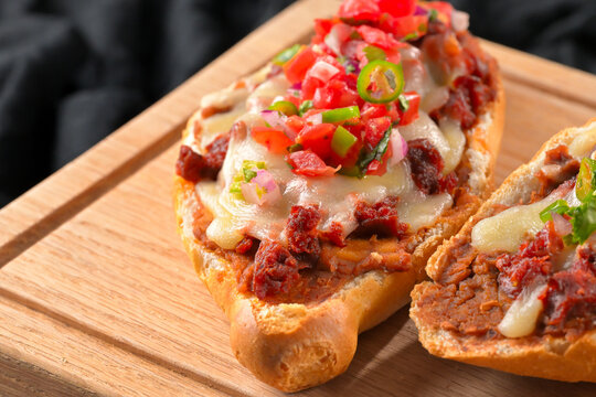 Traditional Mexican breakfast toasted bread with beans, melted cheese, chorizo and pico de gallo