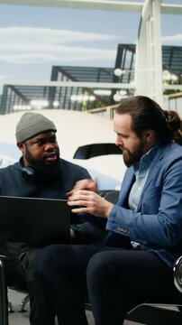 Portrait format: Manager and assistant use a laptop at the airport while preparing to attend an overseas company meeting and travel as a business delegation.