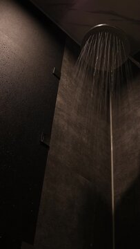 オーバーヘッドシャワー。浴室のレインシャワーから落ちる水。黒いタイル壁
