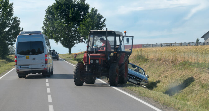 Polska wojew&oacute;dztwo świętokrzyskie, 23 czerwca 2026, 16:38. Traktor Zetor wyciąga kabriolet Mercedes-Benz SLK z przydrożnego rowu. To wiejska sceneria z polami i kilkoma drzewami. Drogą przejeżdża bus