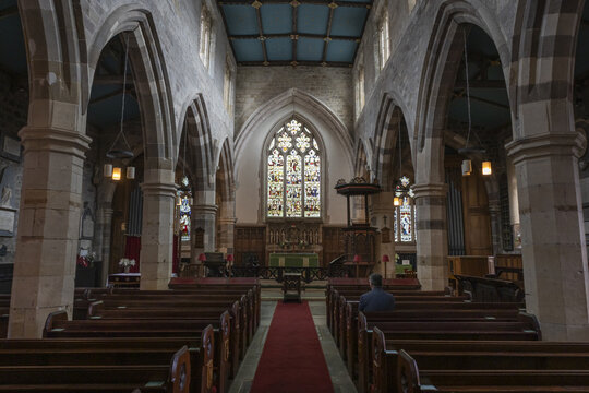 York, United Kingdom - 14 July 2026: View of the interior of a historic church with stone arches, a red carpeted aisle, wooden pews, and a stained glass window.