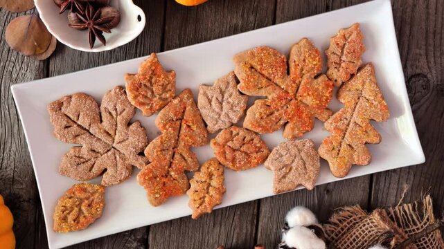 Autumn spiced leaf cookies. Top view on a rustic wood table background. Slow rotating zoom motion.