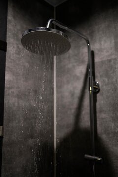 オーバーヘッドシャワー。浴室のレインシャワーから落ちる水。黒いタイル壁