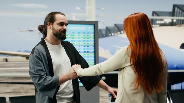 A depressed couple says goodbye and hugs in an airport terminal before departure, sharing a heavy parting moment filled with emotional separation, love and raw sadness between partners.