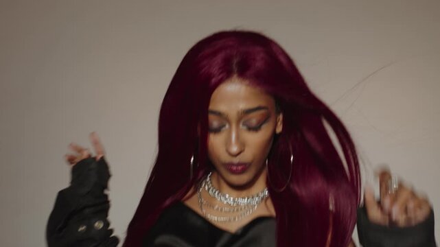 Woman with red hair and bold jewelry sings dynamically in studio