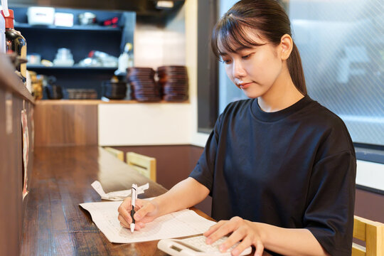 居酒屋で帳簿を確認する女性店長