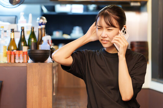 居酒屋で電話対応をする女性店長