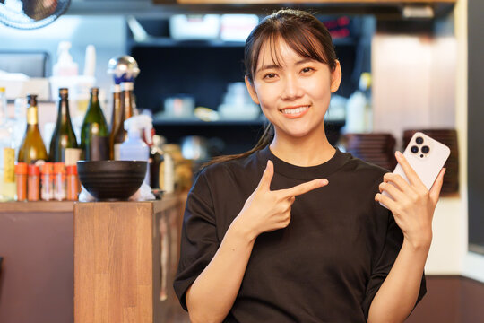 居酒屋でスマートフォンを持つ女性店長
