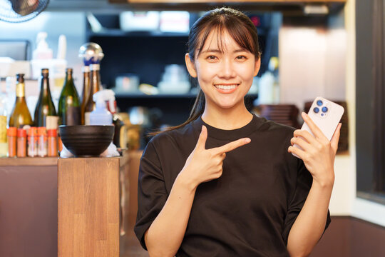 居酒屋でスマートフォンを持つ女性店長