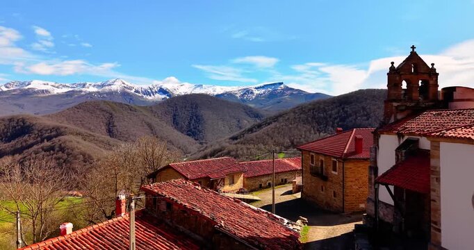 Scenic Aerial Shot of Picturesque European Mountain Village with Church and Snow Peaks. Drone view of San Mames Village in Polaciones with Baroque Church.