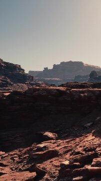 A rocky area shows large stones and mountains in a desert. The sky is clear and bright during the day. This scene captures the rugged terrain and natural features of the outdoors.