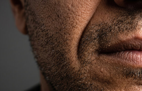 Extreme macro close up of rough skin texture large pores and stubble beard on lower face of mature man.