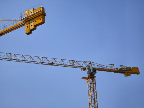 Construction Tower Crane with Two Extended Arms against a Clear Blue Sky