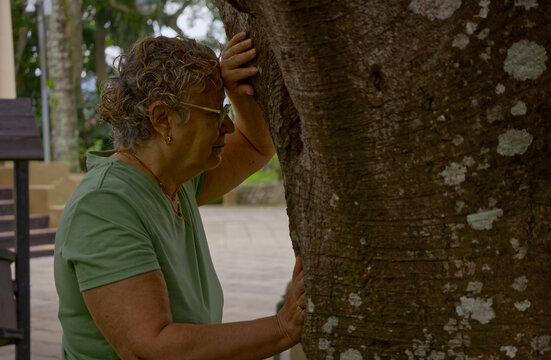 Senior woman resting against a tree during an outdoor walk