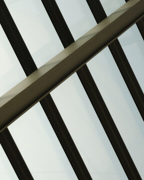 Abstract view of steel beam and glass roof panels creating geometric lines and modern architectural patterns with clean industrial design.