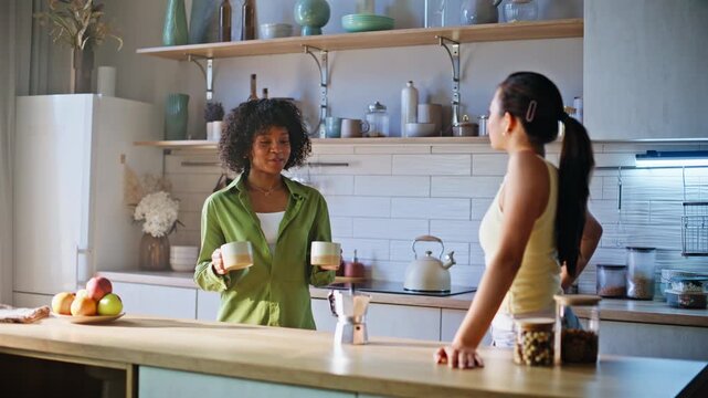 Girlfriends brewing coffee kitchen. Two women pouring moka pot into cups home.