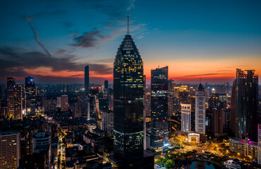 Fototapeta premium Aerial twilight view of Wuhan Financial Street CBD. The towering, illuminated skyscrapers reflecting in the water symbolize the dynamic growth of China's economy. 