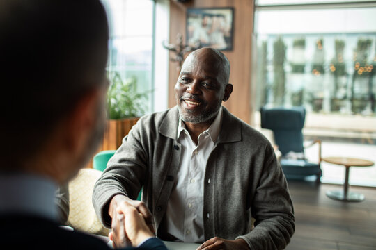 Smiling businessman shaking hands during meeting in modern cafe