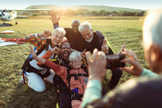 Senior friends celebrating skydiving landing at sunset airfield