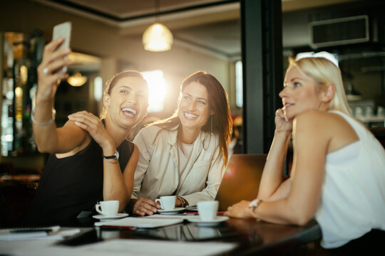 Three businesswomen taking a selfie at a cafe meeting